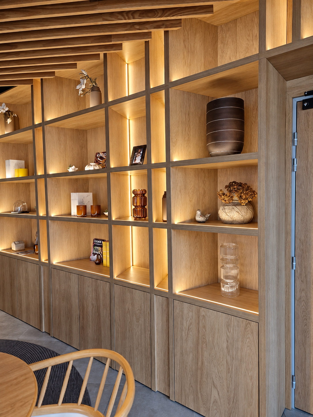 Bibliothèque toute hauteur en bois clair, niches éclairées, rangements bas